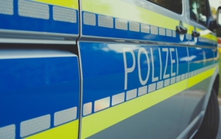 Ermittlungen am ONG Polizei Auto von der Seit mit Schriftzug "Polizei" im Vordergrund